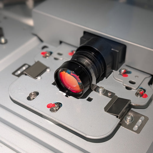 Close-up of a camera lens on a metal mount with visible wiring.