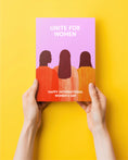 Load image into Gallery viewer, Flyer with 'Unite for Women' text and silhouette design held against a yellow background

